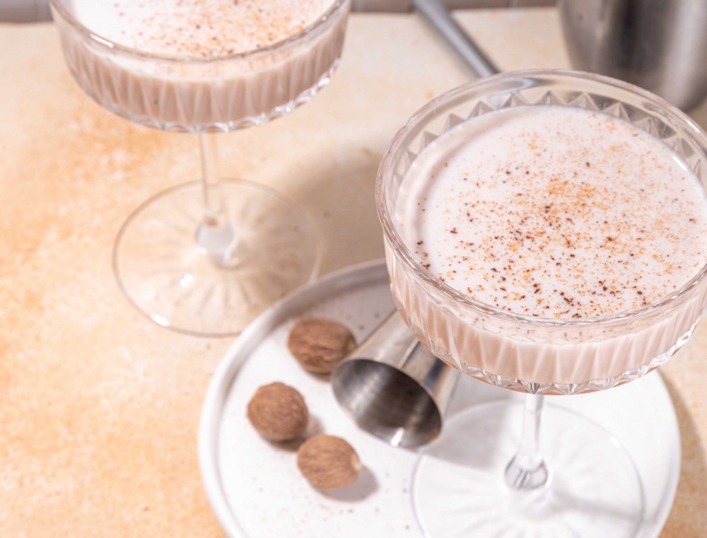 Coppe di champagne riempite del cocktail Alexander con schiuma e noce moscata grattugiata sopra. Colori tendenti al caffÃ¨ latte. corsi Studio Aschei per diventare barman