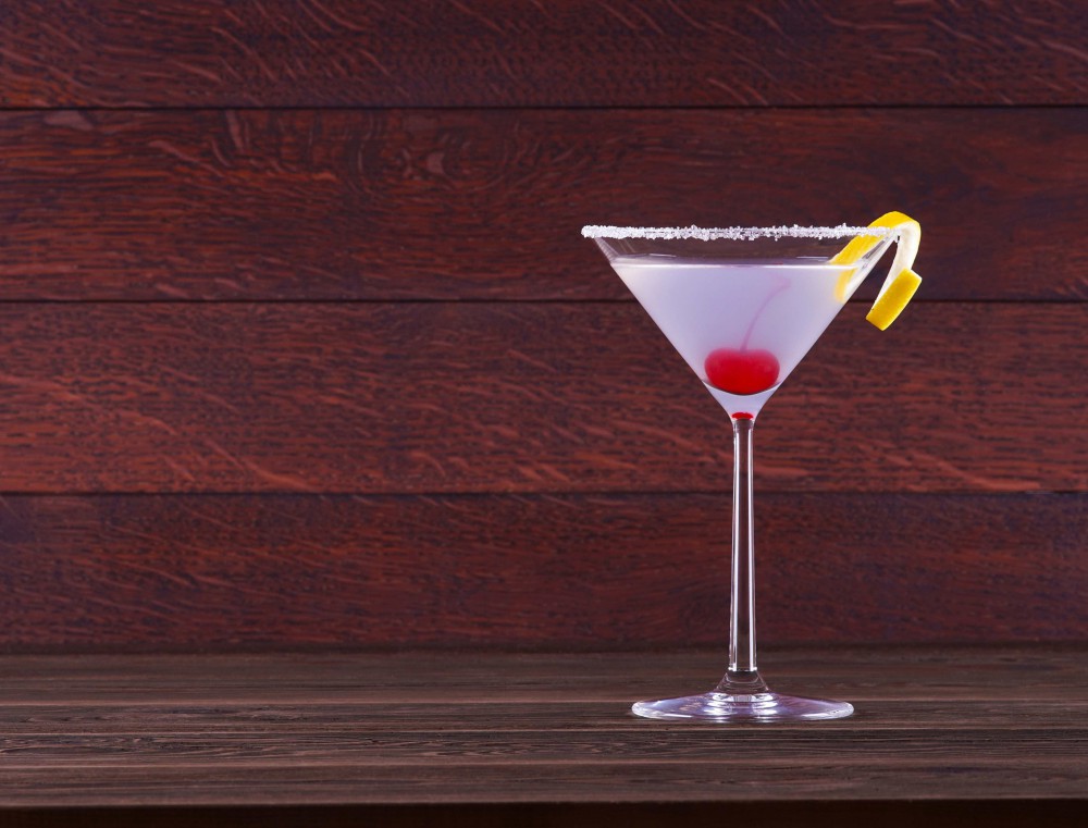 Meravigliosa foto di cocktail in colore tendente al viola in bicchiere coppa martini su sfondo di legno rovere scuro.